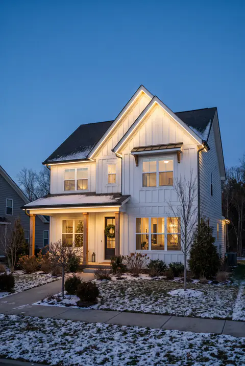 Modern farmhouse with permanent LED track lights mounted under the eaves glowing warm white along every roof edge