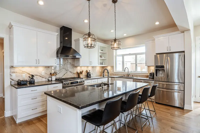 Elegant modern kitchen with high-gloss white cabinets and matte black countertops showcasing a minimalist island and stainless steel appliances