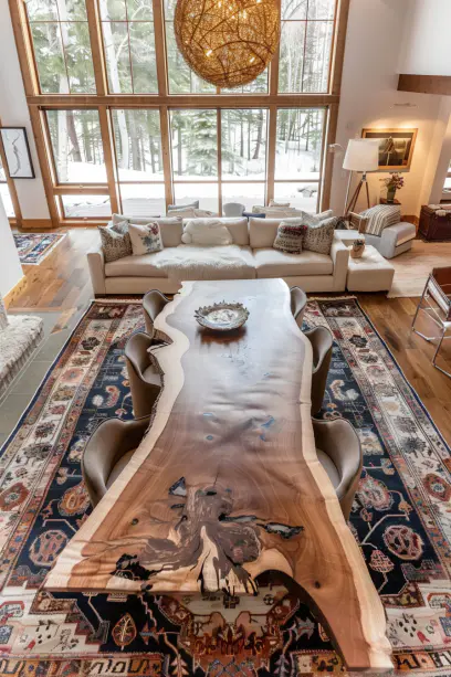Panoramic view of an open-plan living and dining area in an American home featuring a live edge dining table and textured rug