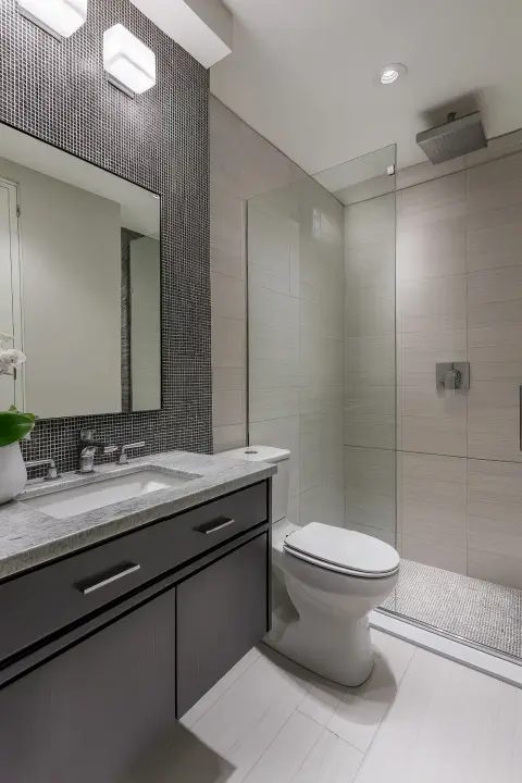 Modern bathroom with a shower glass door granite countertop and patterned black tile wall