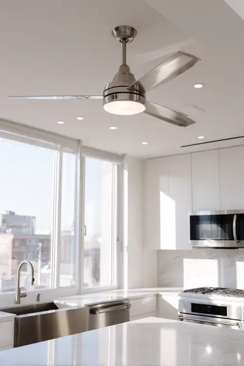 A sleek, modern kitchen ceiling fan with an integrated light fixture, installed above a clean white island. This stylish kitchen ceiling light solution provides both illumination and a cool breeze.
