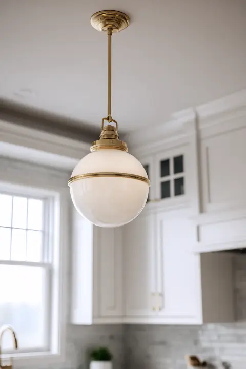 A stylish semi-flush mount kitchen ceiling light with a frosted glass globe and brass accents hangs over a white marble island in a bright, modern farmhouse kitchen. Perfect decorative overhead lighting.