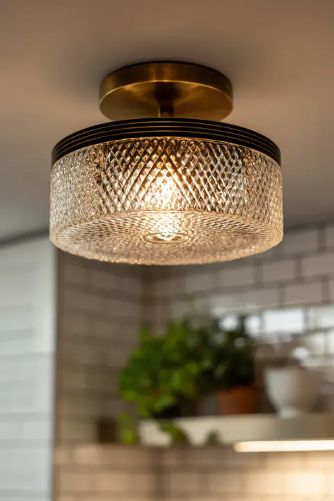 Close-up detail of a modern flush mount kitchen lighting fixture with textured glass and bronze finishes. A beautiful and compact kitchen ceiling light solution for homes with low ceilings.