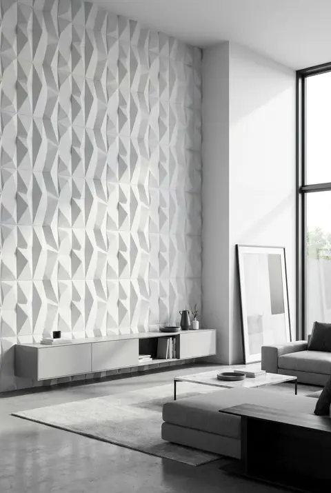 Minimalist contemporary living area showcasing a white 3D geometric textured accent wall, a sleek grey floating media console, concrete flooring, and a modern grey sectional sofa.